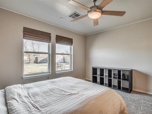 carpeted bedroom with a textured ceiling, ceiling fan, and crown molding