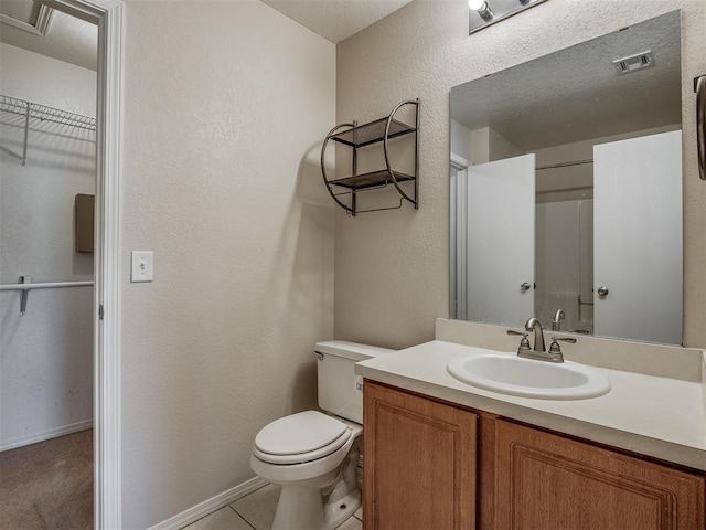 bathroom featuring tile patterned flooring, a textured ceiling, vanity, and toilet