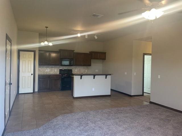 kitchen featuring a kitchen bar, tasteful backsplash, carpet, and black appliances