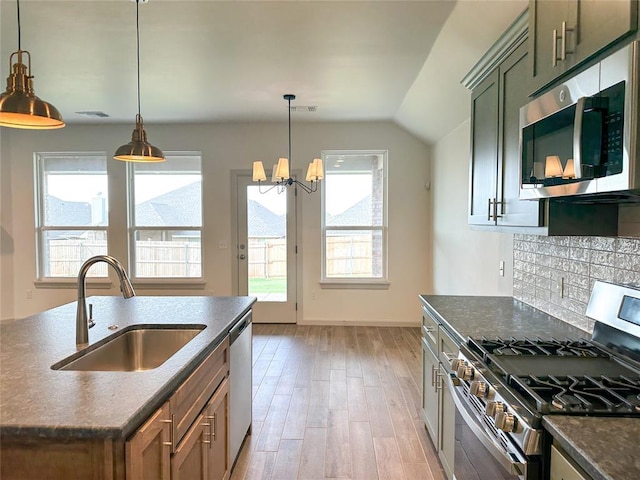 kitchen with stainless steel appliances, sink, light hardwood / wood-style flooring, a chandelier, and hanging light fixtures