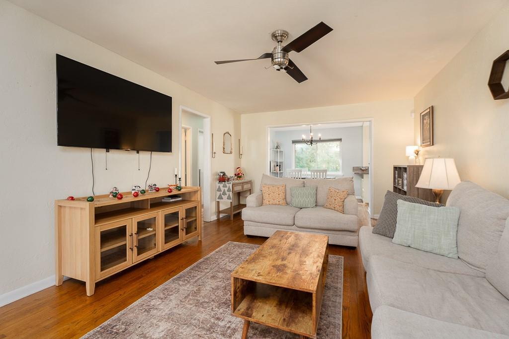 living room with ceiling fan with notable chandelier and hardwood / wood-style flooring