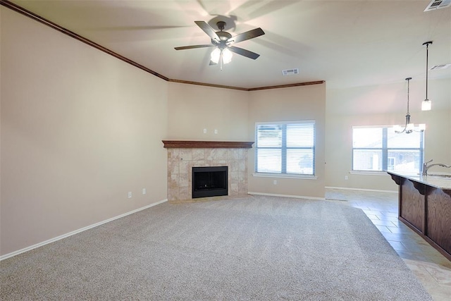 unfurnished living room featuring ceiling fan, sink, crown molding, light carpet, and a fireplace