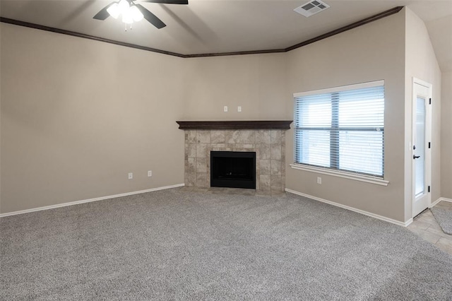 unfurnished living room with ceiling fan, ornamental molding, light carpet, and a tiled fireplace