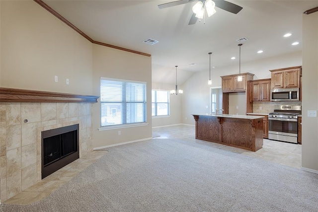 kitchen with pendant lighting, stainless steel appliances, a kitchen island, and light colored carpet