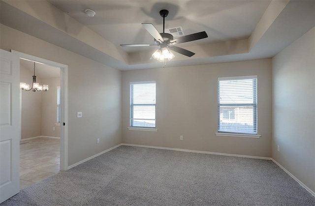 unfurnished room with a tray ceiling, a wealth of natural light, and light carpet