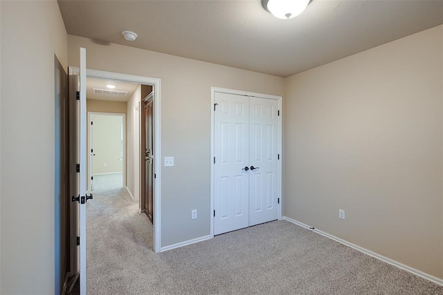 unfurnished bedroom featuring a closet and light colored carpet