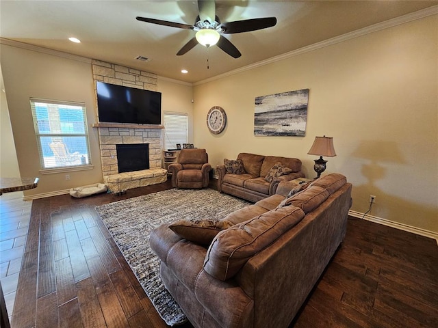 living room featuring ornamental molding, a stone fireplace, dark hardwood / wood-style floors, and ceiling fan