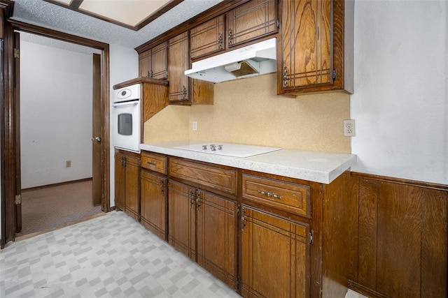 kitchen featuring electric cooktop, white oven, and a textured ceiling