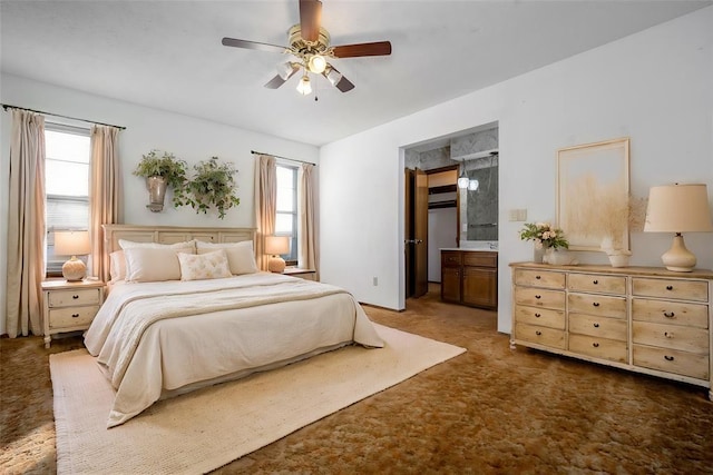 bedroom featuring dark colored carpet, ensuite bathroom, and ceiling fan