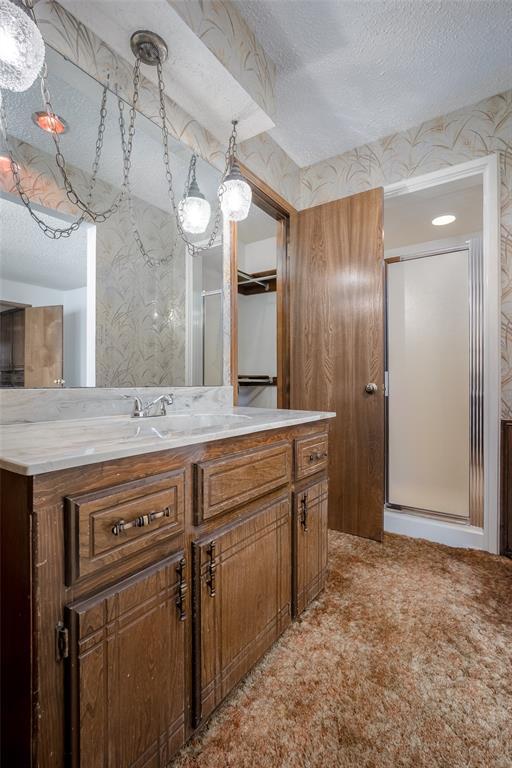 bathroom with walk in shower, vanity, and a textured ceiling