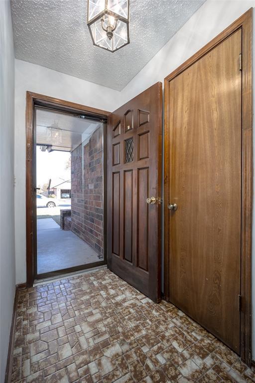 foyer entrance with a chandelier and a textured ceiling