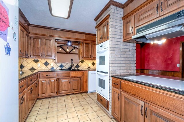 920173 S 3450th Rd, Chandler, OK 74834 - kitchen with under cabinet range hood, dark countertops, white appliances, a sink, and ornamental molding