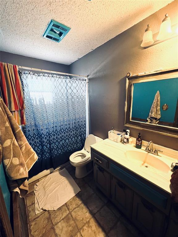 bathroom featuring tile patterned flooring, vanity, toilet, and a textured ceiling