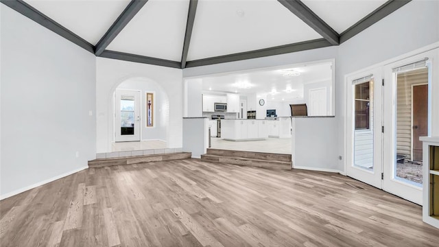 unfurnished living room featuring lofted ceiling with beams and light hardwood / wood-style floors