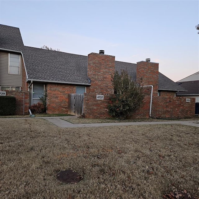 4727 NW 72nd St, Oklahoma City, OK 73132 - back of property at dusk with brick siding, a shingled roof, and a chimney