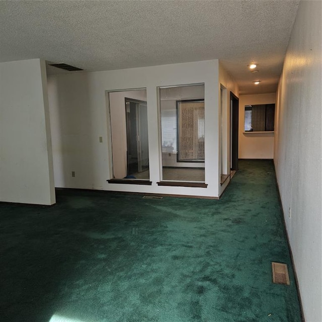 carpeted empty room featuring a textured ceiling