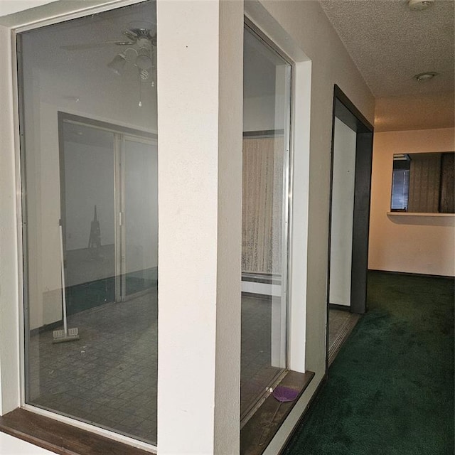 corridor featuring a textured ceiling and dark colored carpet