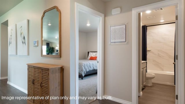 hall featuring wood finished floors, visible vents, and baseboards