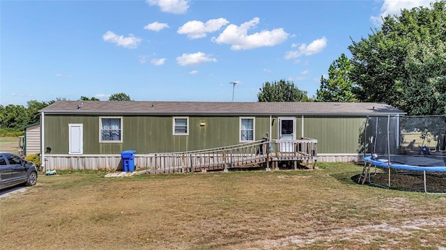 view of front of house featuring a trampoline, a wooden deck, and a front lawn