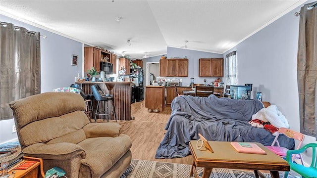 living room with crown molding, lofted ceiling, and light wood-type flooring