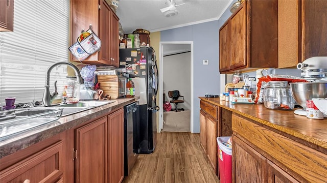 kitchen featuring lofted ceiling, black appliances, sink, light hardwood / wood-style flooring, and ornamental molding