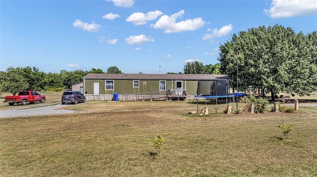 view of front of house featuring a front lawn, a deck, and a trampoline