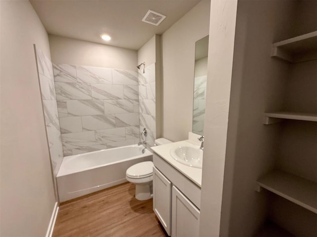 full bathroom with hardwood / wood-style flooring, toilet, vanity, and tiled shower / bath