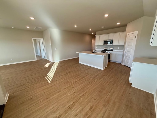 kitchen featuring white cabinets, light hardwood / wood-style flooring, stainless steel appliances, sink, and a center island with sink