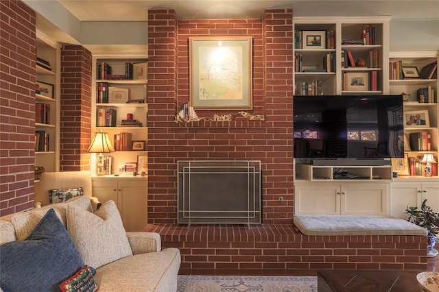 living room featuring built in features, a fireplace, and brick wall