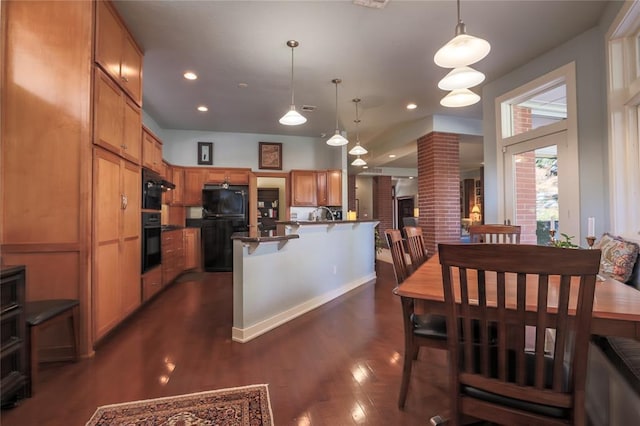 kitchen featuring a breakfast bar area, black fridge, dark hardwood / wood-style flooring, and decorative light fixtures