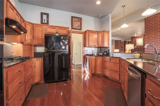 kitchen featuring sink, hanging light fixtures, stainless steel appliances, dark hardwood / wood-style flooring, and dark stone countertops