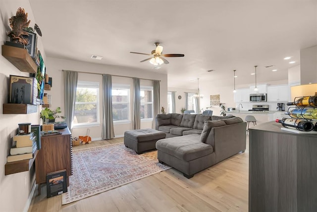 living room featuring ceiling fan, light hardwood / wood-style flooring, and sink