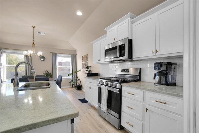 kitchen with pendant lighting, sink, light wood-type flooring, appliances with stainless steel finishes, and white cabinetry