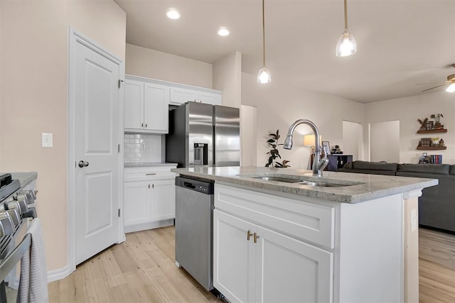 kitchen featuring a center island with sink, white cabinets, hanging light fixtures, sink, and appliances with stainless steel finishes