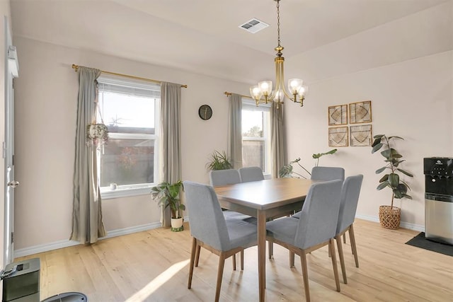 dining area with light hardwood / wood-style flooring, a healthy amount of sunlight, and a notable chandelier