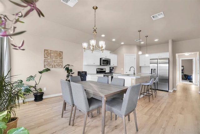 dining space featuring sink, a notable chandelier, and light wood-type flooring