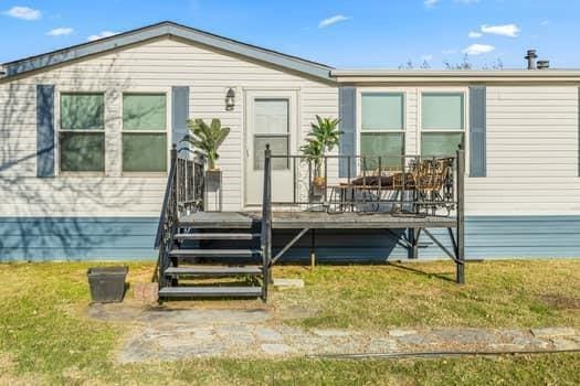 rear view of property featuring a yard and a deck