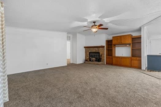 unfurnished living room with a fireplace, carpet floors, and ceiling fan