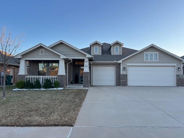 craftsman inspired home with covered porch, a front yard, and a garage