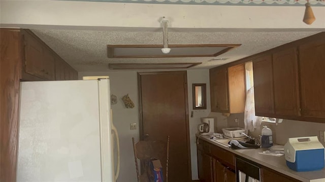 kitchen with a textured ceiling, white fridge, and sink