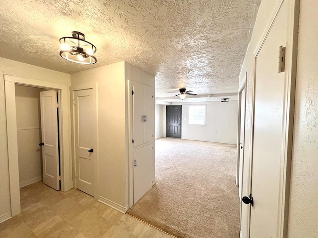 corridor with light colored carpet and a textured ceiling