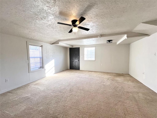 unfurnished room featuring carpet flooring, a textured ceiling, a wealth of natural light, and ceiling fan