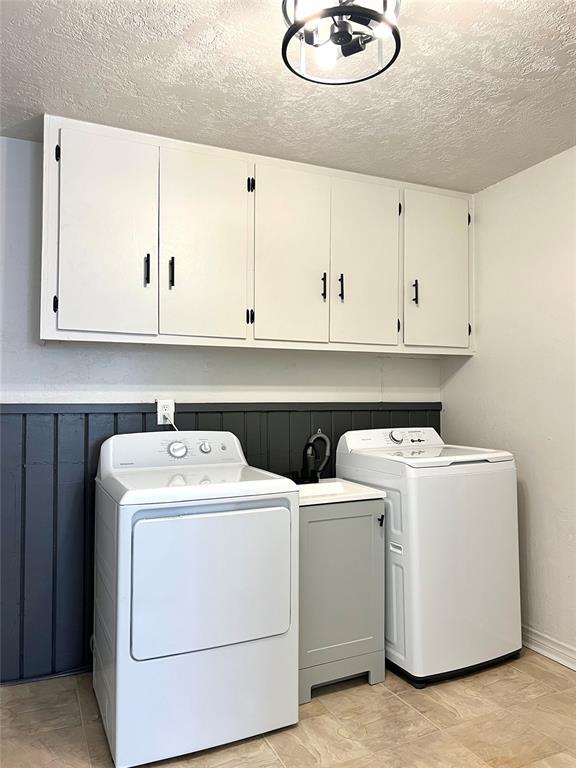 laundry area featuring cabinets, a textured ceiling, and washer and clothes dryer