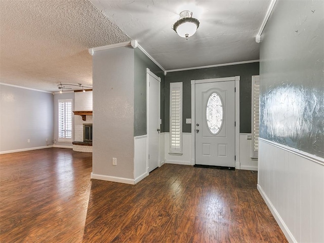 foyer featuring a fireplace, a textured ceiling, dark hardwood / wood-style floors, and crown molding