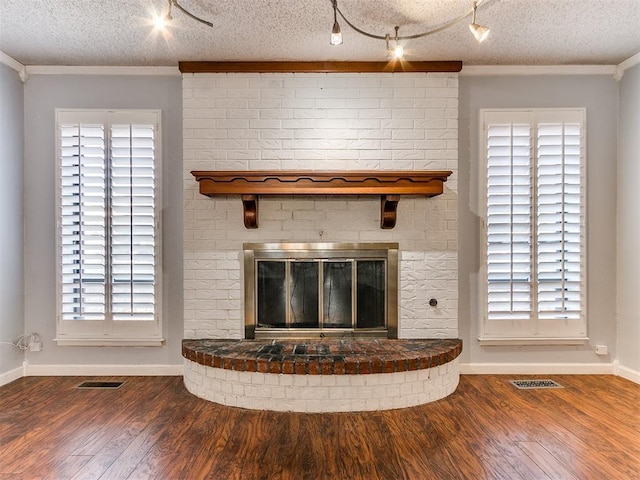 room details with crown molding, a fireplace, a textured ceiling, and hardwood / wood-style flooring