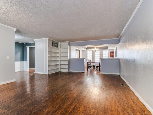 unfurnished living room with dark wood-type flooring, an inviting chandelier, built in features, a textured ceiling, and ornamental molding