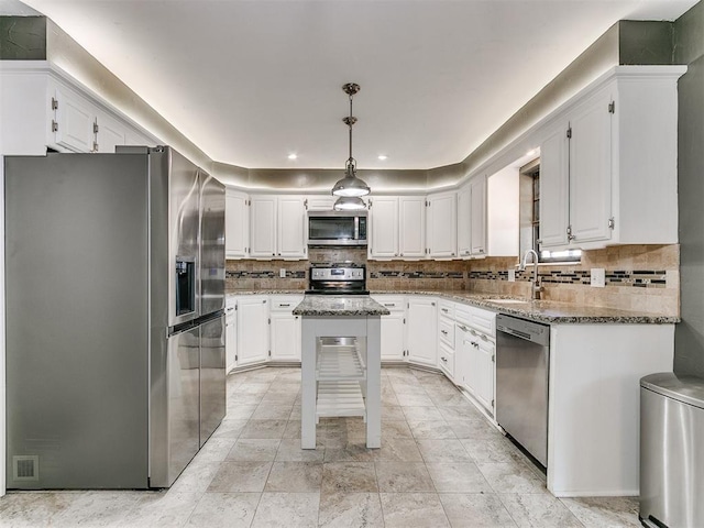 kitchen featuring pendant lighting, a center island, light stone countertops, appliances with stainless steel finishes, and white cabinetry