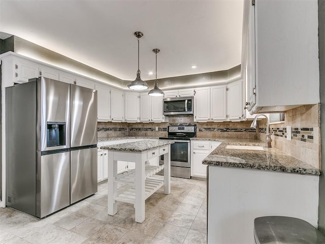 kitchen with appliances with stainless steel finishes, sink, pendant lighting, dark stone countertops, and white cabinetry