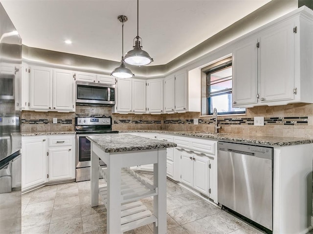 kitchen featuring hanging light fixtures, stainless steel appliances, light stone counters, and white cabinetry