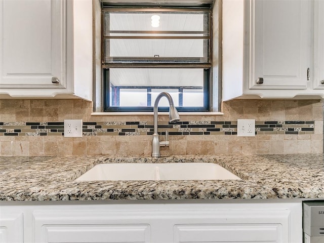 kitchen with backsplash, light stone countertops, sink, and white cabinets